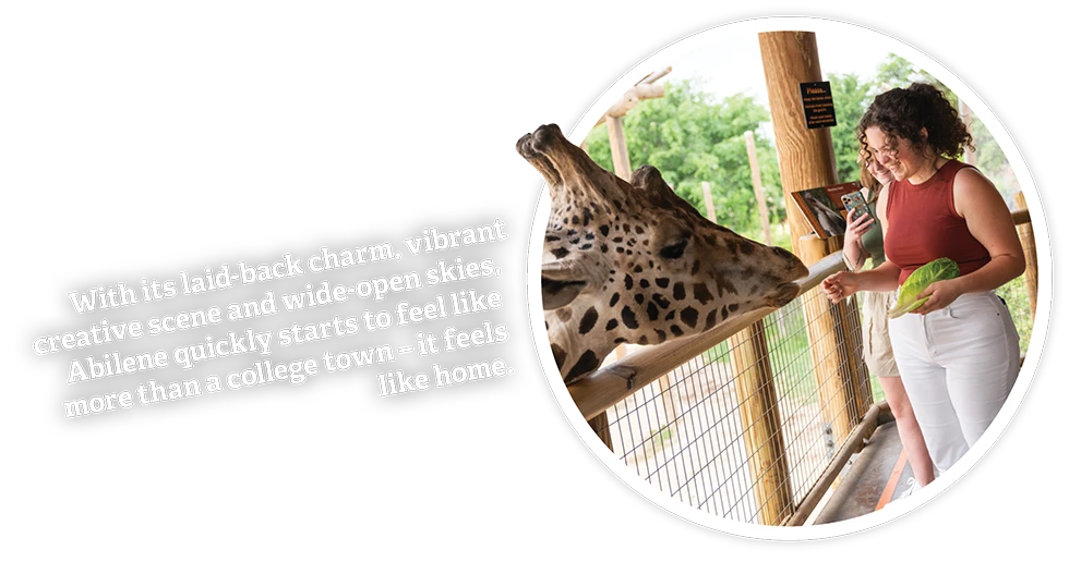 Text on the left reads: 'A place that will soon feel like your second home. Cozy up with a book at a local coffee shop or gather your friends for game night. Either way, Abilene is student-friendly. Abilene is relaxing and fun.' On the right, a young woman is feeding a giraffe at a zoo, smiling, with another person taking a photo in the background.