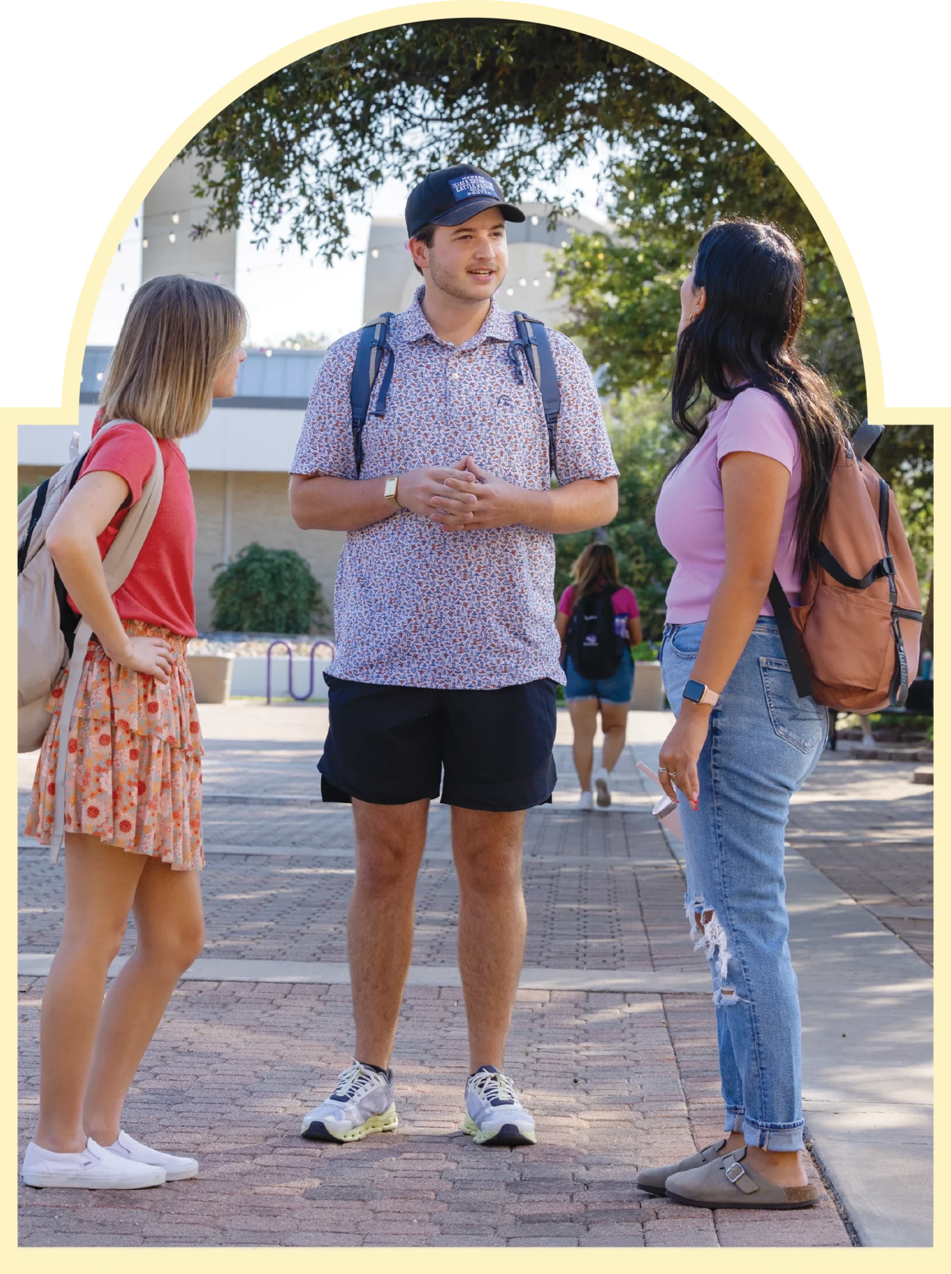 Three ACU students talk together outdoors on campus.