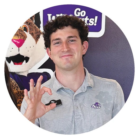 ACU student smiles and makes a hand sign during a campus visit.