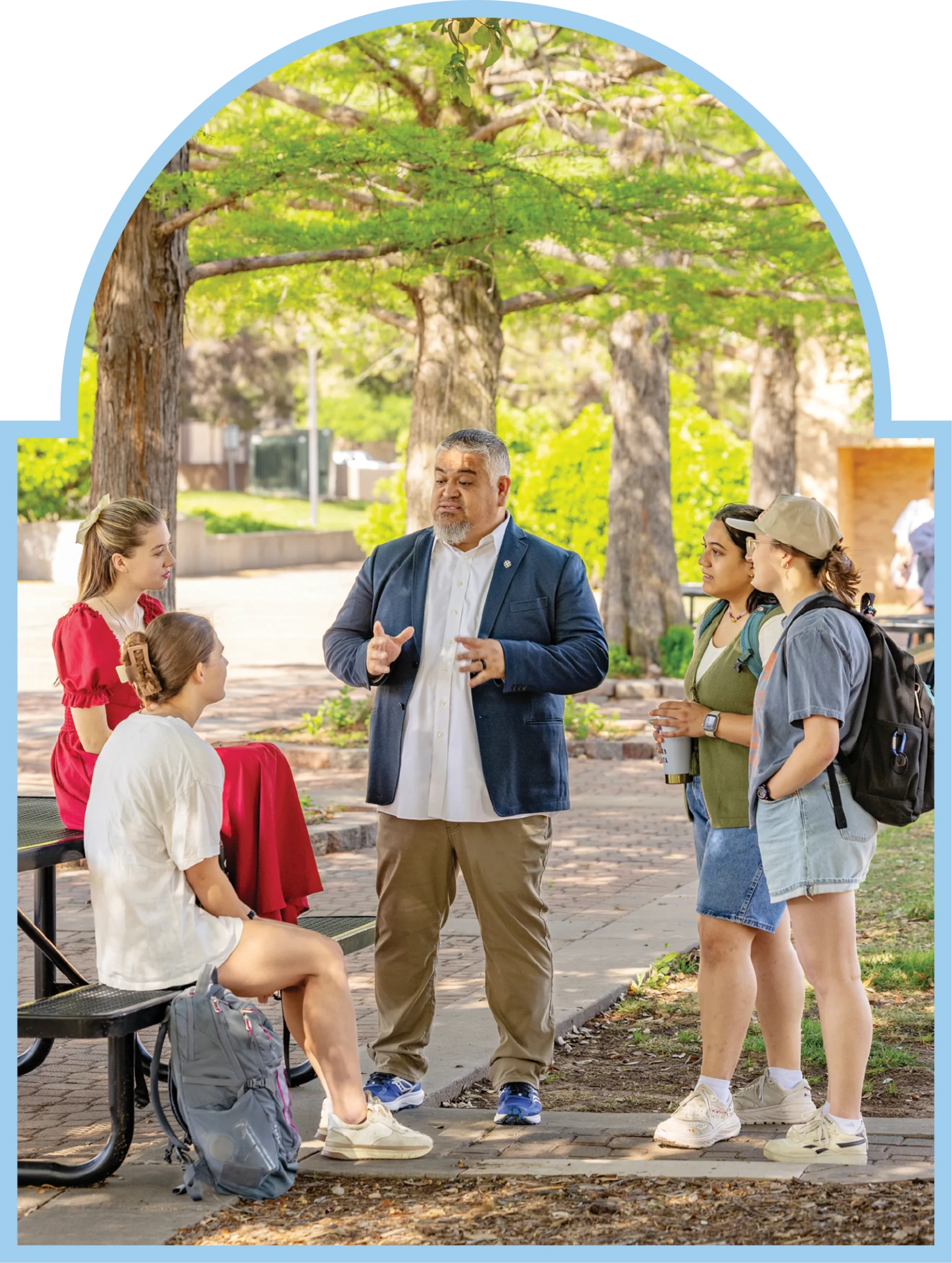 ACU faculty member talks with students outdoors on campus.
