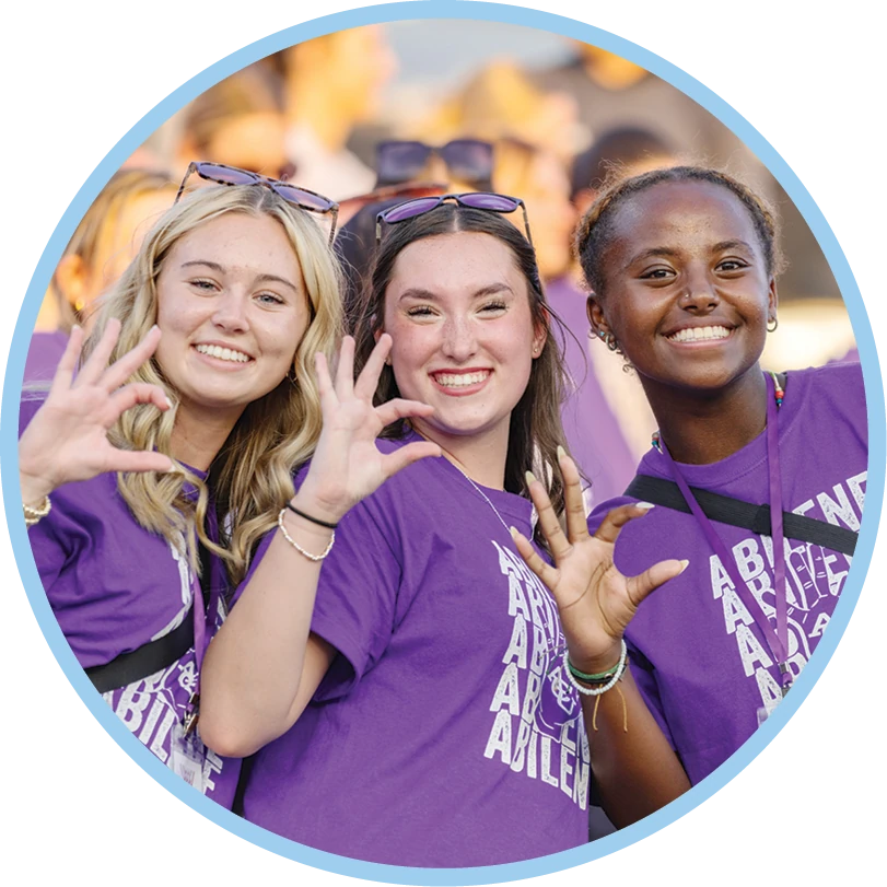 Three ACU students smile together at a campus event.