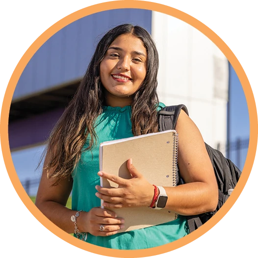 ACU student holds books and smiles outdoors.