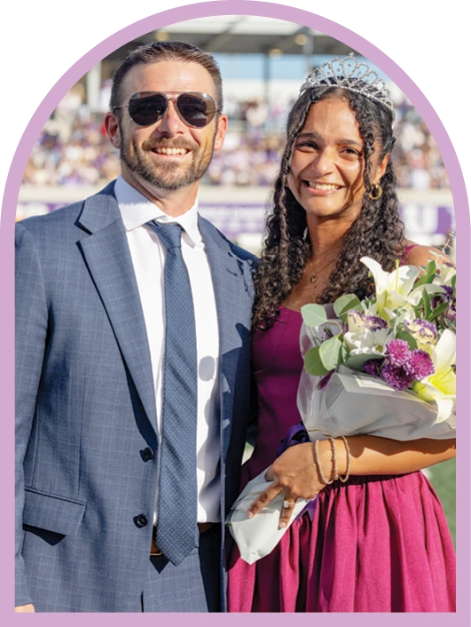 ACU student and companion posing with flowers at a campus celebration.