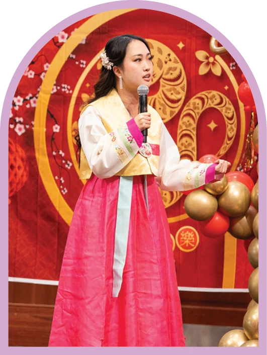 Student speaking at a cultural celebration while wearing traditional Korean dress.