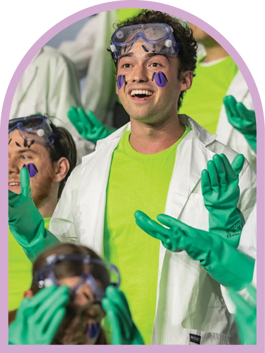 Student performer in bright green costume and face paint during Sing Song.
